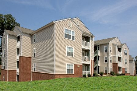a row of apartment buildings on a green field